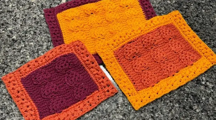 An image of three crochet trivets made with the tunisian leaf and heart stitches in three fall colors, a golden yellow, burgundy, and burnt orange.