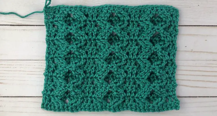 Treble Cross Stitch crochet tutorial image of green yarn with zig zag cables on the surface and double crochet between three columns of the zig zag cables.
