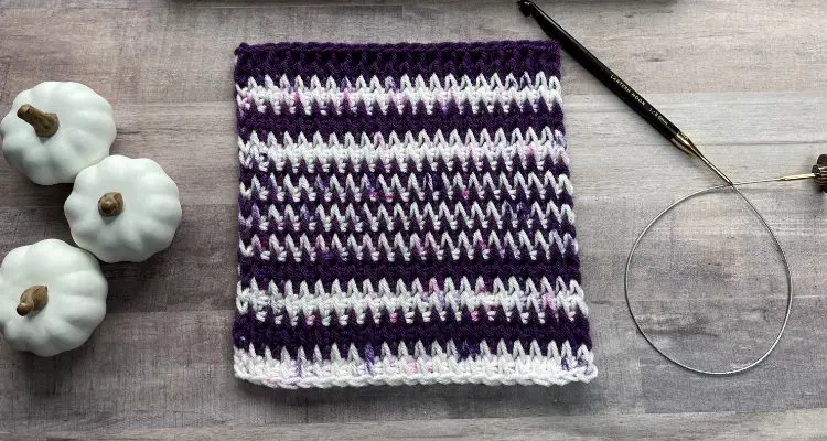 The Heartbeats Tunisian Square is made with purple and white with purple flecked yarn the alternating colors appear to create spikes that look similar to an EKG or ultrasound.