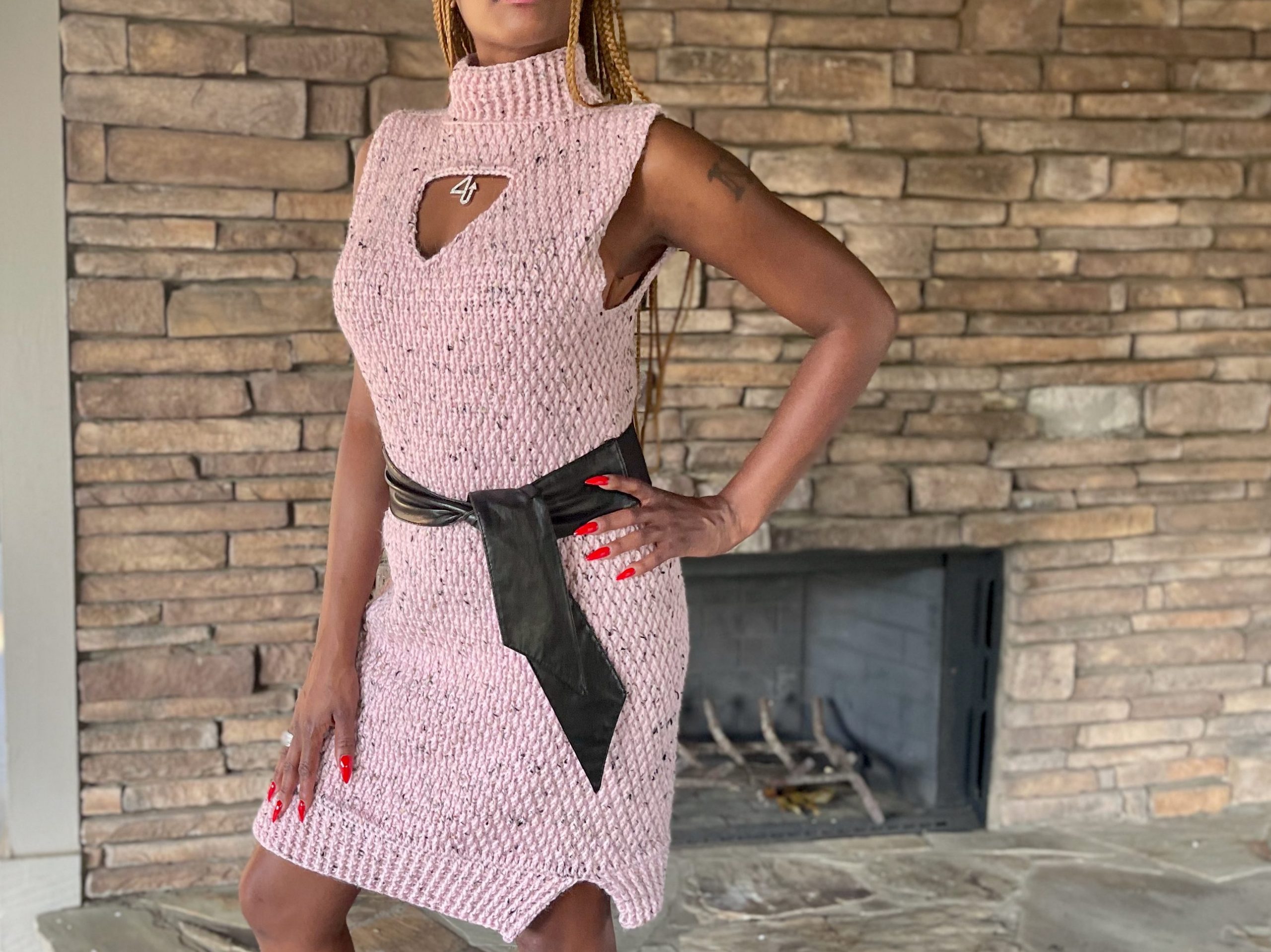 Textured, pink crochet dress that is sleeveless and worn with a wide belt tied around the waist.