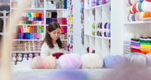 An image of a woman looking at a wide selection of yarn to make a crochet garment.
