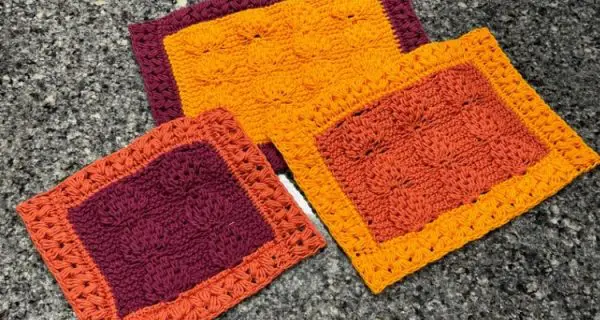 An image of three crochet trivets made with the tunisian leaf and heart stitches in three fall colors, a golden yellow, burgundy, and burnt orange.