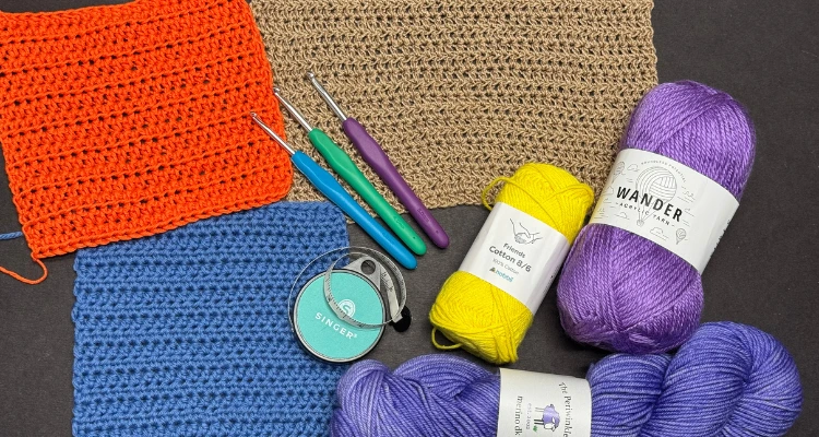 An image of crochet hooks, three crochet swatches in different yarns and colors, a tape measure and three skeins of yarns that are different weights and fiber contents that can be used for making crochet garments.