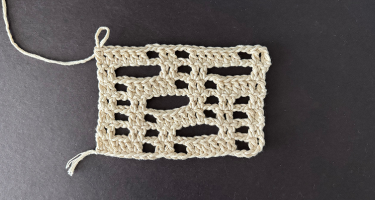An image of a crochet rectangle made of double crochet and chain spaces in a cream colored yarn for a crochet lace tutorial.