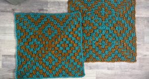 Two finished overlay mosaic crochet square samples in turquoise and brown yarn placed side by side on a light wood surface. The overlay mosaic crochet square pattern forms a geometric star and diamond motif with textured stitches that create a raised mosaic effect.